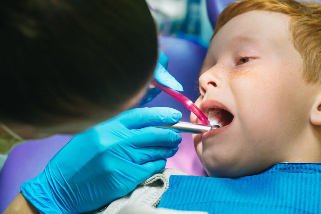 a woman checks a child's teeth as part of essential dental services